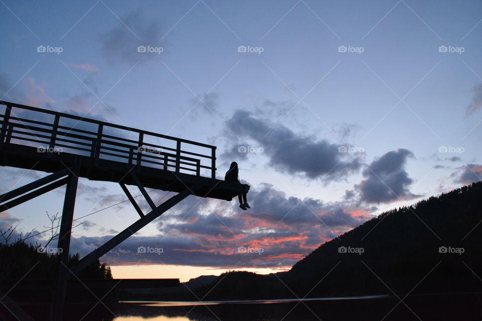 Silhouette of girl sitting on bridge