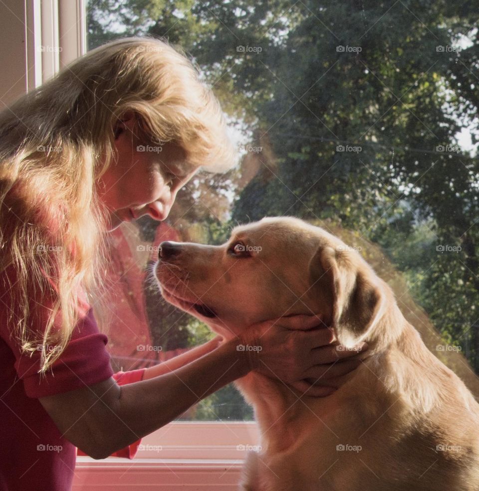 Blonde woman and yellow lab looking into each other’s eyes