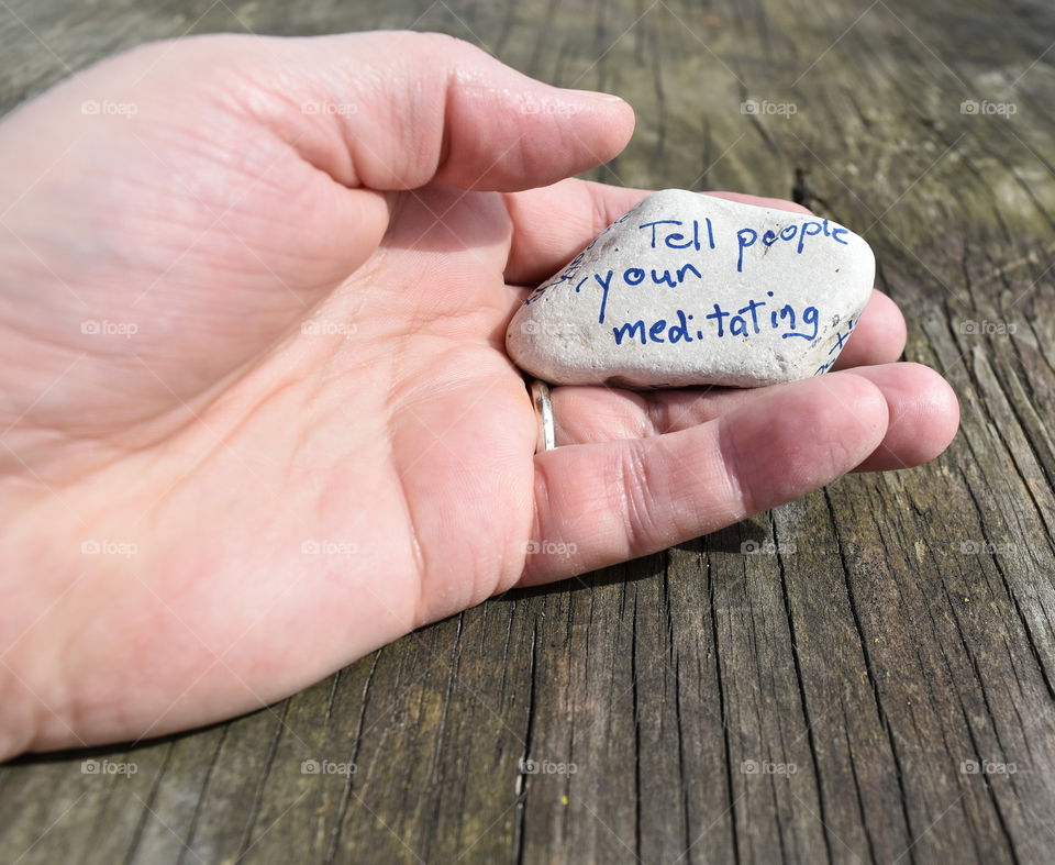 Hand holding a stone with an affirmation written on it