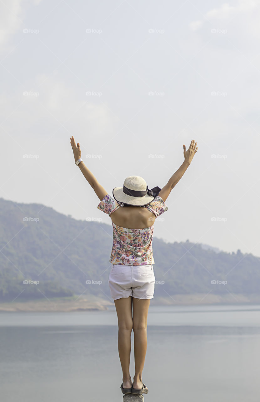 Women raise their arms Background mountains and water at Khun Dan Prakan Chon Dam ,Nakhon Nayok in Thailand.