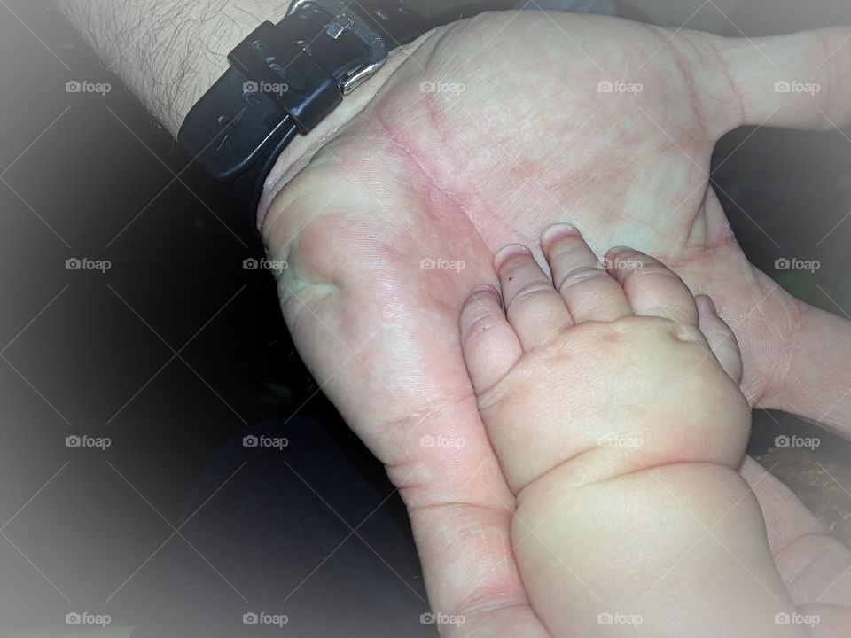 Baby’s hand in the palm of Dad’s hand.