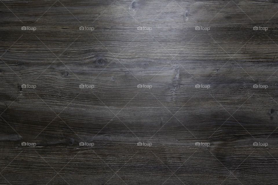 A gray wooden surface that is used as a background with a light feeding from the left side.