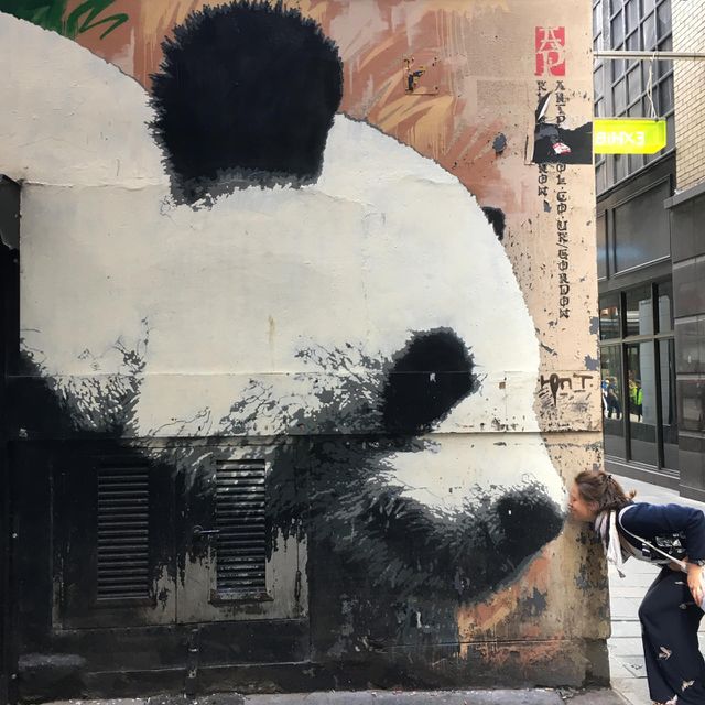 Street art in Glasgow, Scotland. Panda bear head with woman kissing it’s nose! Panda Art on building wall. 