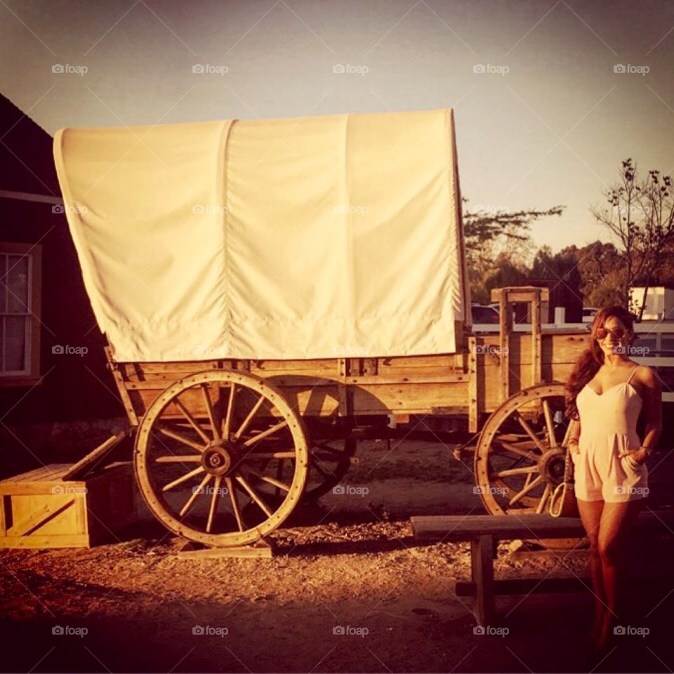 Portrait of a woman posing besides wooden cart