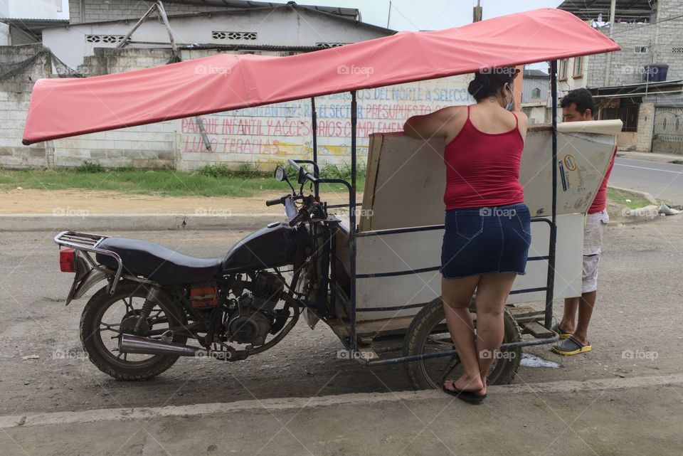 Woman shopping in a cart on the street.