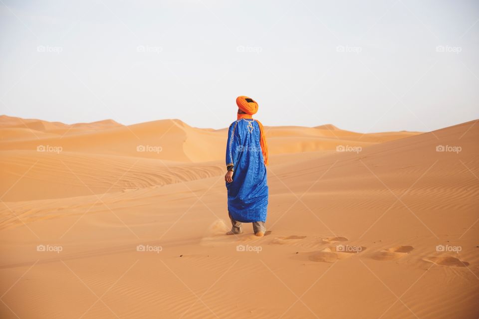 Sahara desert, Morocco. A man walking in traditional dress. 