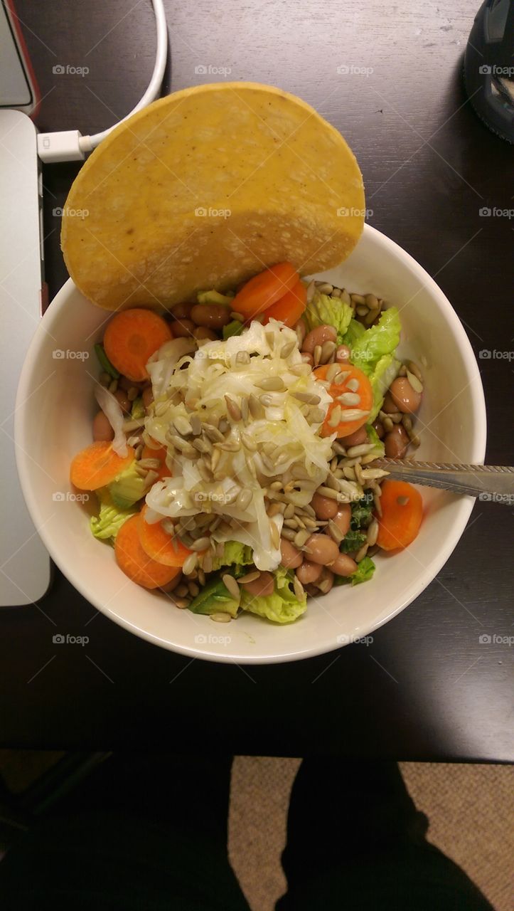 Raw Vegan meal with carrots sunflower seeds lettuce pinto beans sauerkraut and tortilla