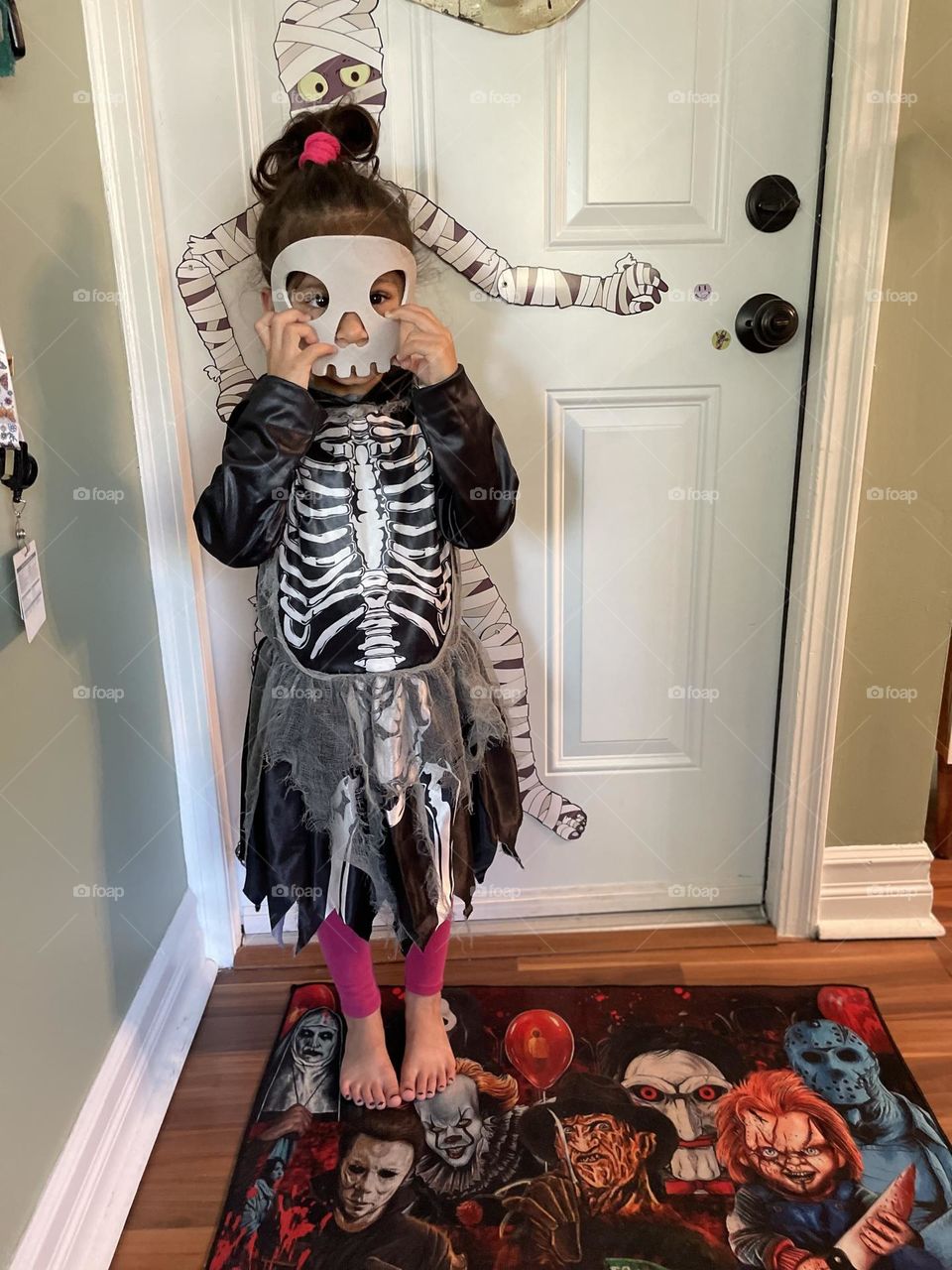 Little girl puts on scary skeleton costume, trying to scare mommy, scary skeleton Halloween costume, wearing costumes for trick or treat 