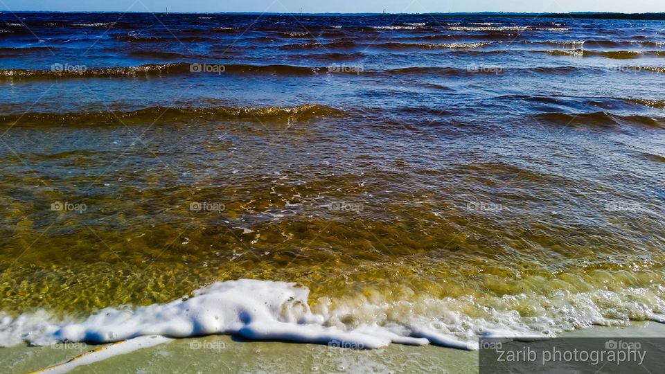 lake merge with the skyline, wind forming waves and foam at the shoreline.