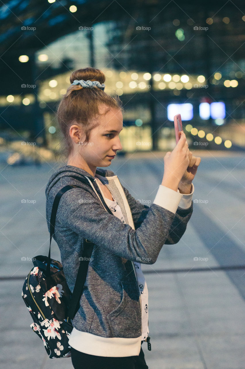 Young woman taking photos using a smartphone in the city at night