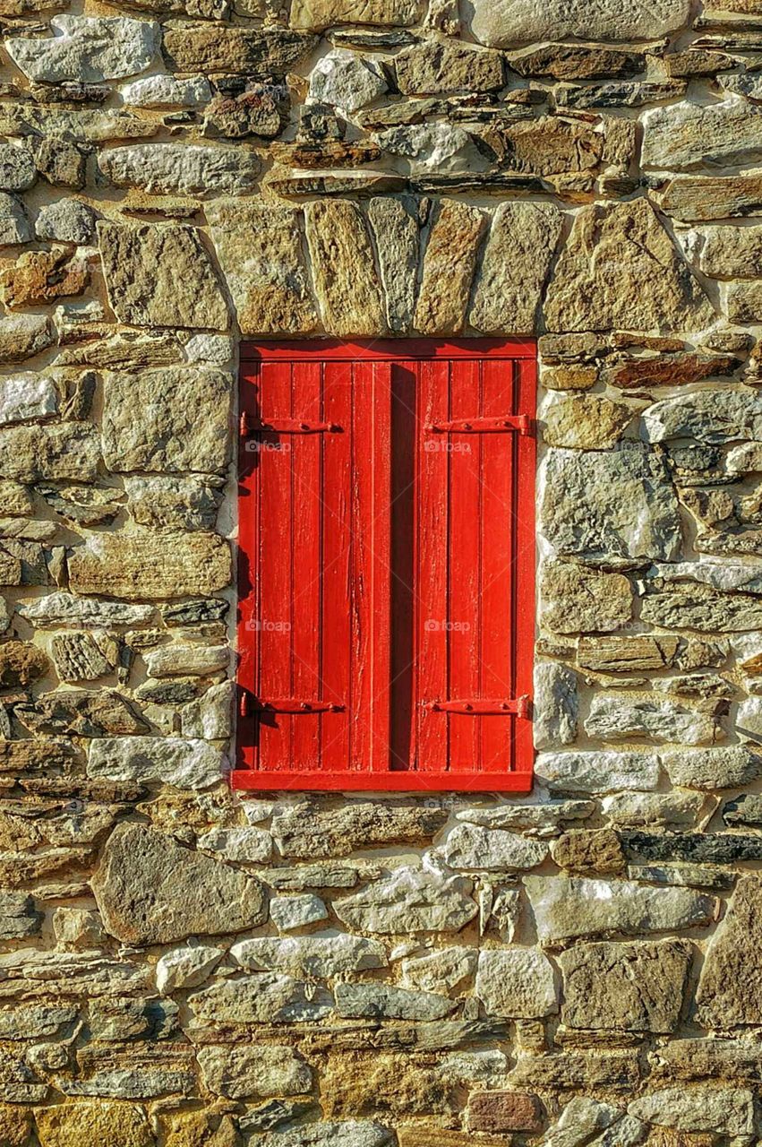 red painted wood shutters in stone wall