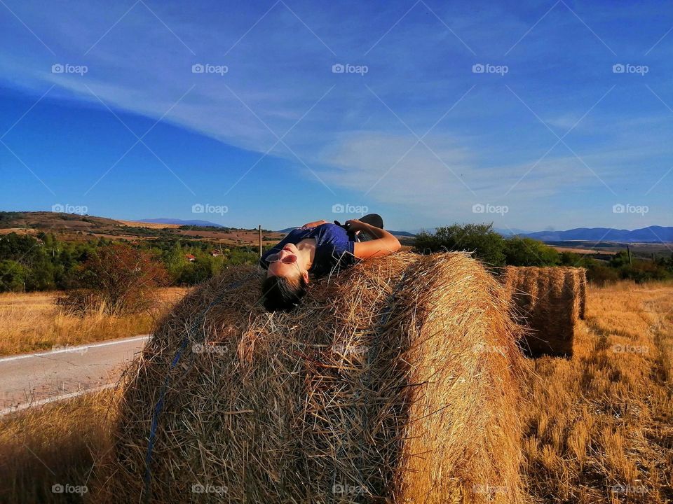 A beautiful photo of a girl lying on a bale in a field in Bulgaria in the hot summer