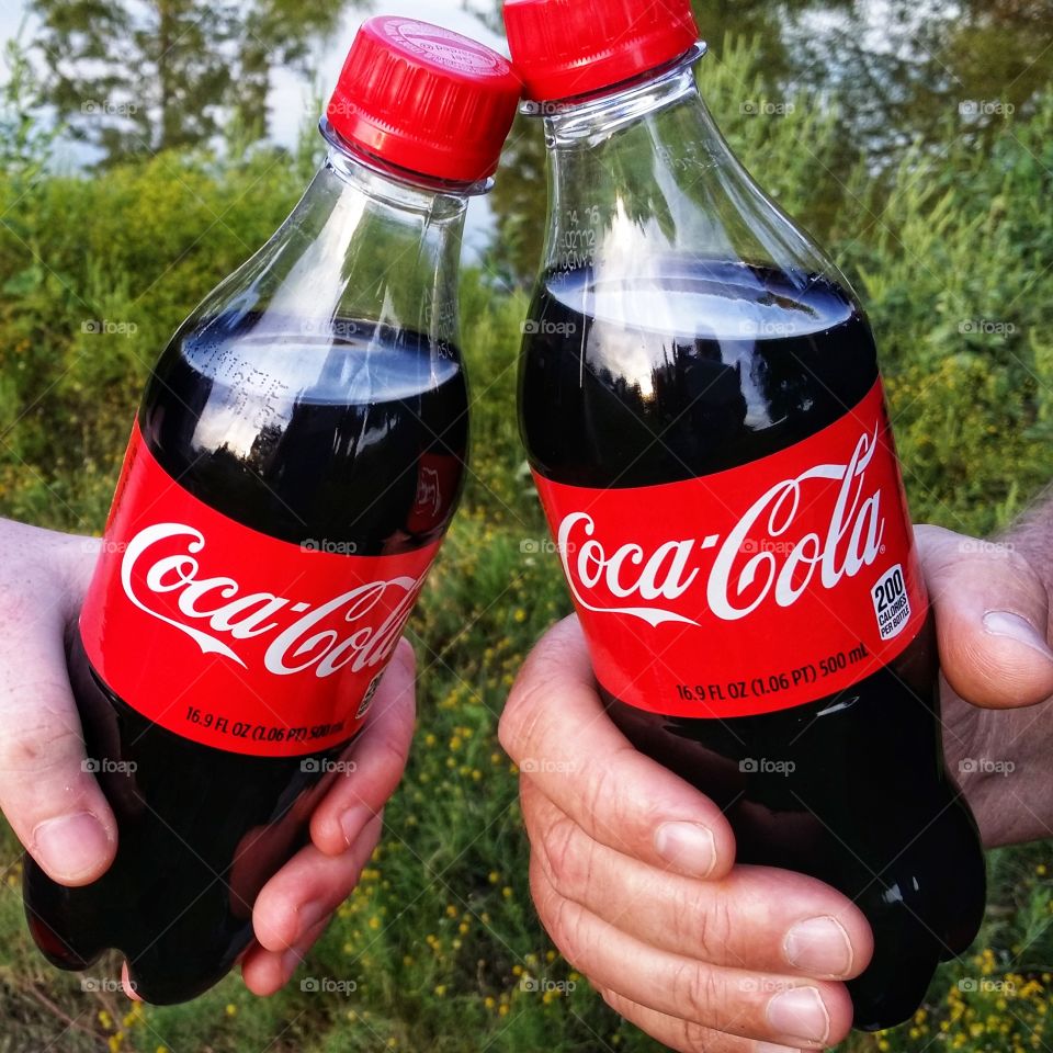 Two men holding Cokes