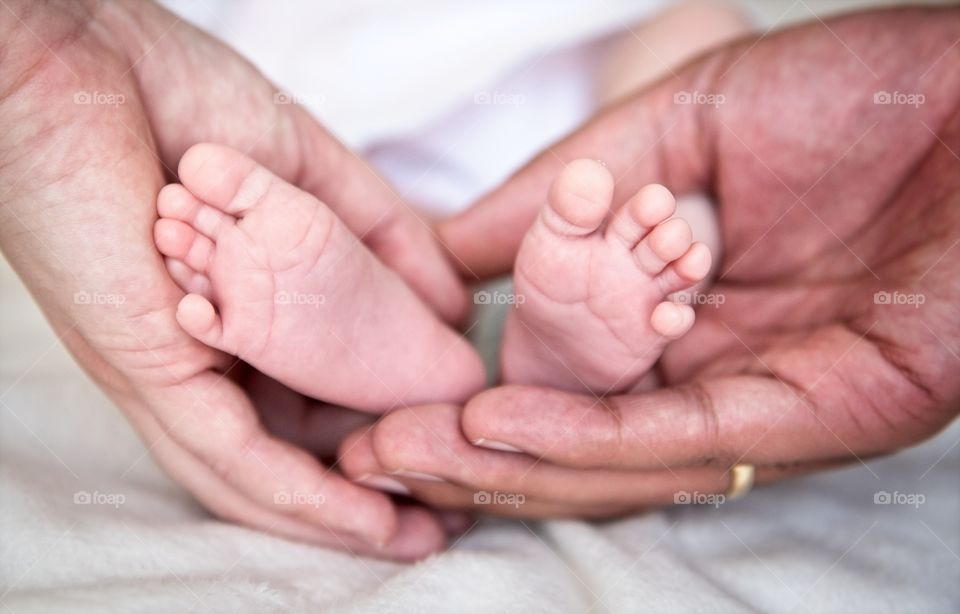 Newborn baby feet in her parents hands
