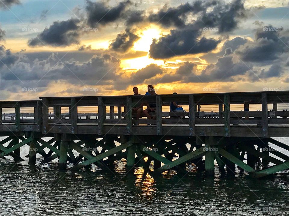 People watching the sunset from a fishing pier 