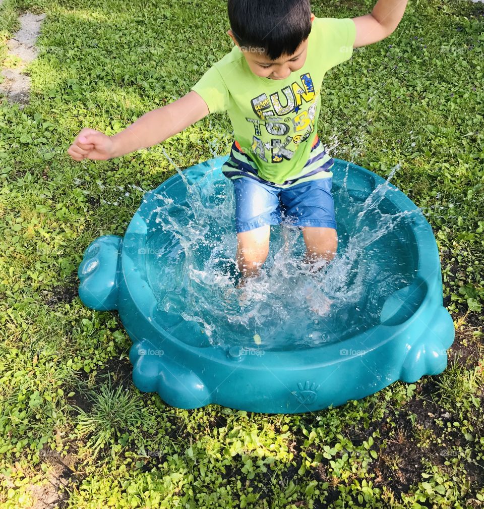 Boy jumping into a small water pool