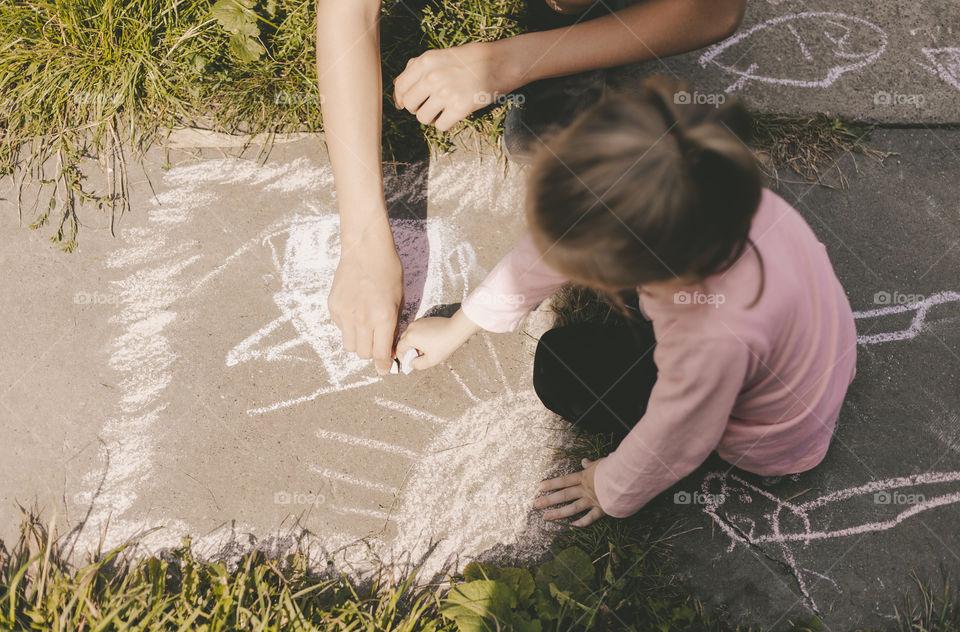 Children draw with chalk on the asphalt.
