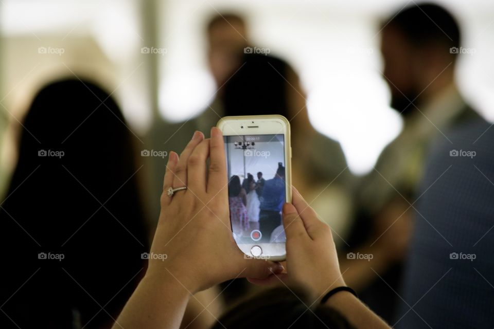 Person holding mobile phone to get a photo or video of first dance