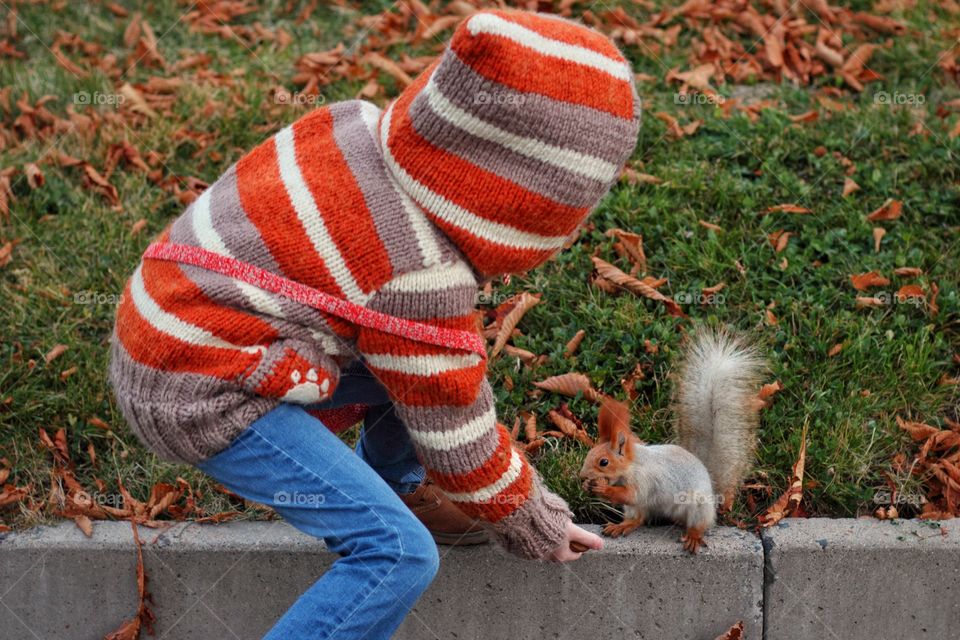 Child feeds a squirrel in the park in autumn