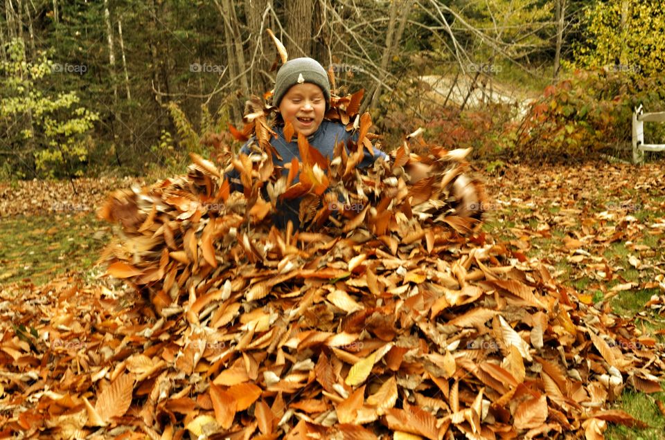 Girl surrounded with autumn dry leaves