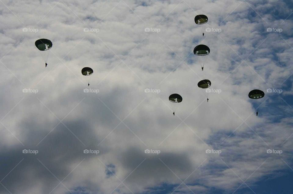 WWII paratroopers dropping in a cloudy sky