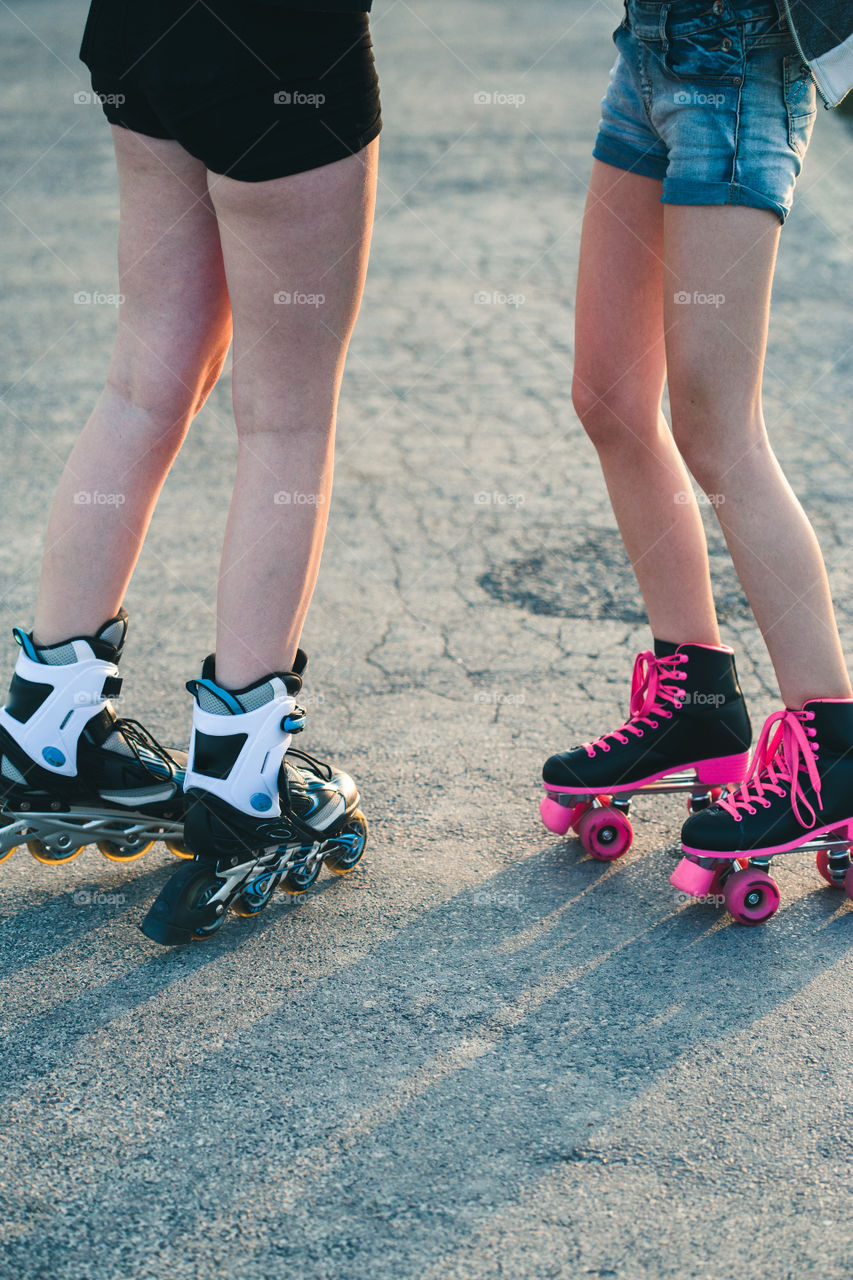 Teenage girl having fun rollerskating, jumping, spending time on summer day. Teenage smiling happy girls having fun walking outdoors, hanging, spending time together on summer day. Real people, authentic situations