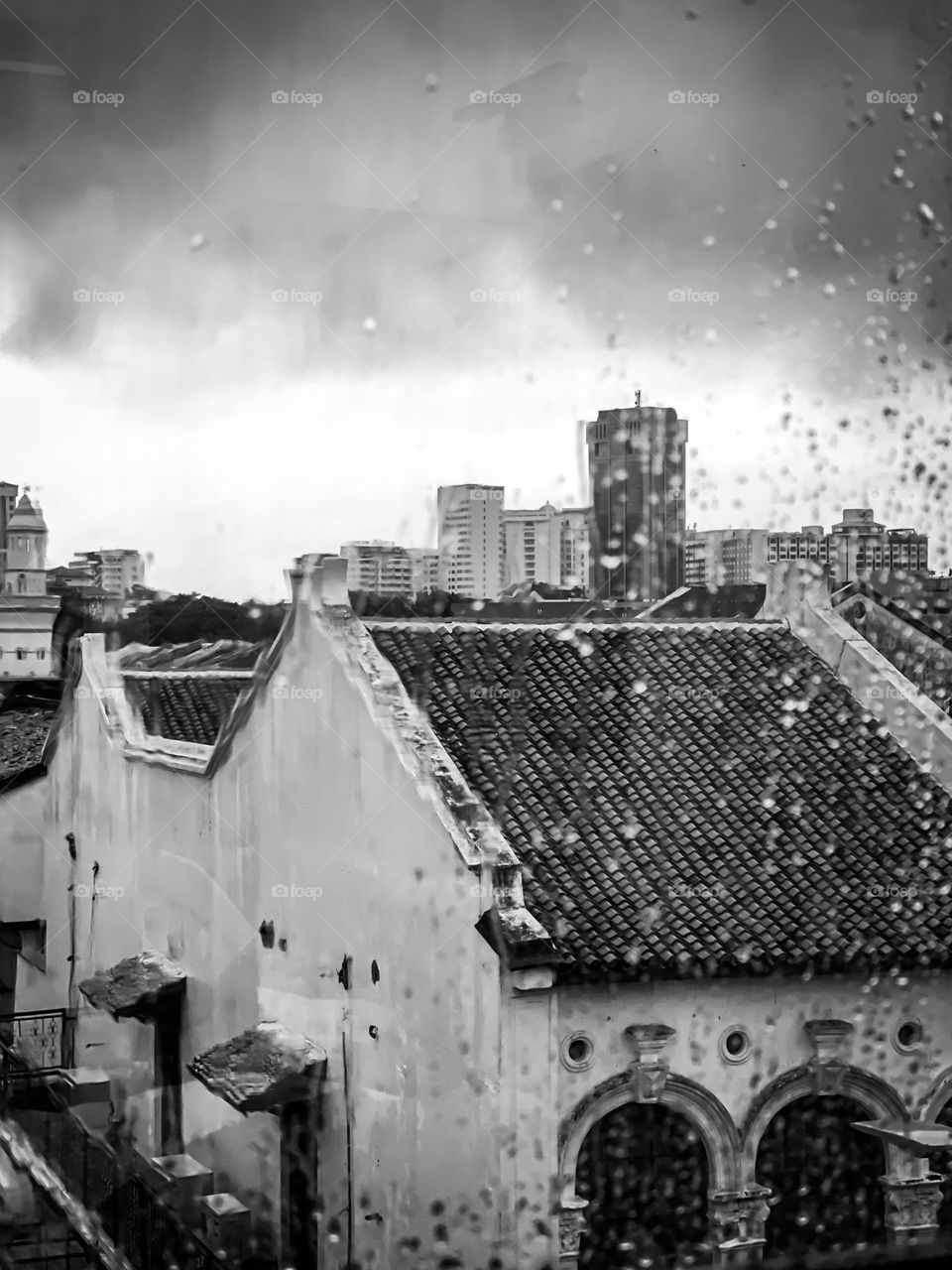 Black and white buildings and some water drops on the window shield 