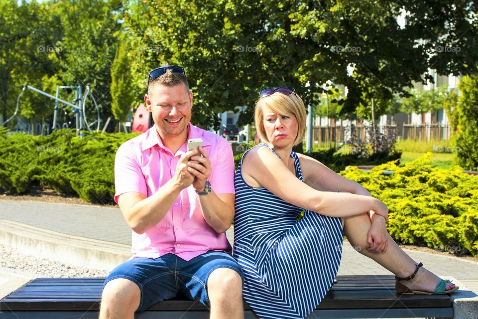 
Close up of couple in disinterest moment with smart phone in the outdoor, concept of relationship apathy and isolating using new technology and smartphone addiction
