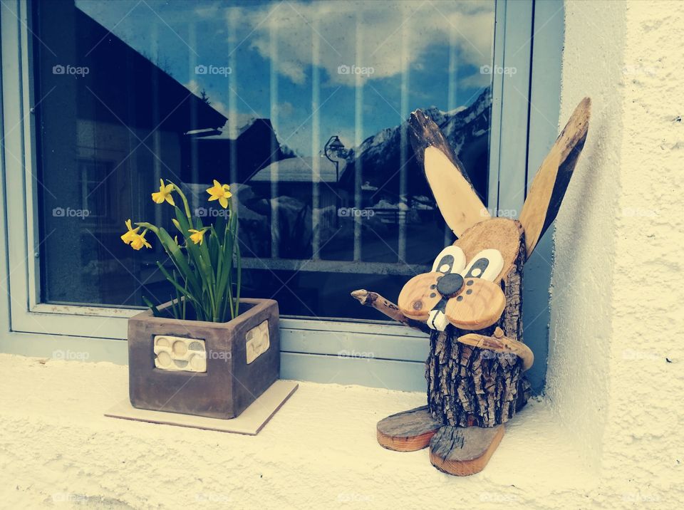 Easter bunny at the window and yellow daffodils at the sill