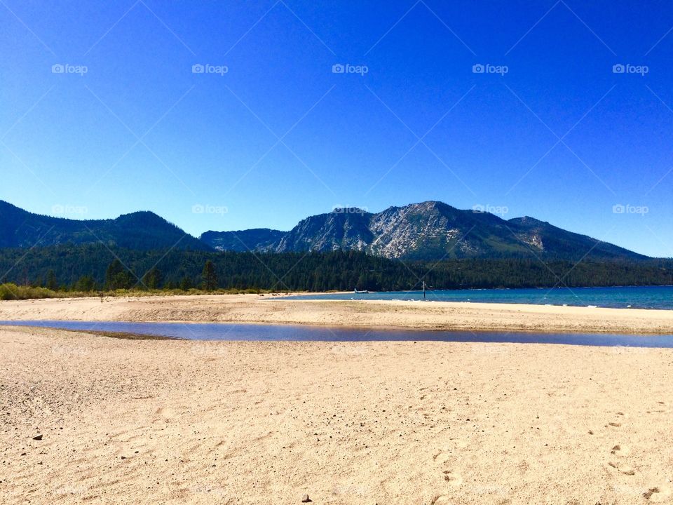 Scenic view of trees and mountain, against blue sky