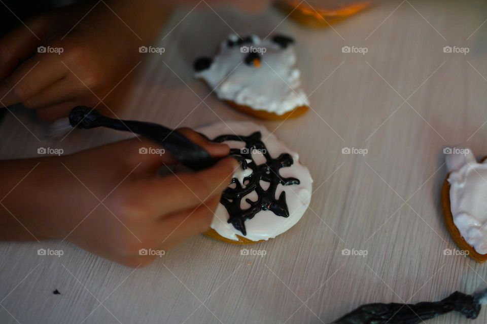 seven year old boy decorating handmade cookies for Halloween