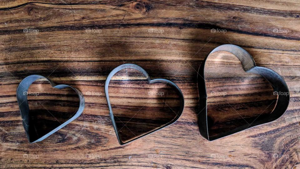 3 heart cookie cutters on a wooden cutting board