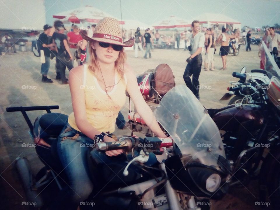 girl in a hat and jeans on a motorcycle. bike festival. summer