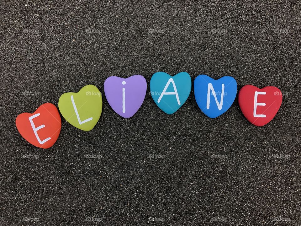 Eliane, feminine name with colored heart stones over black volcanic sand