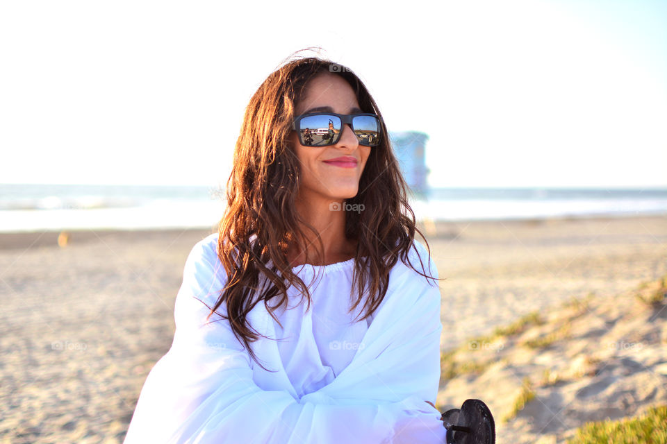 Beach hair brunette woman in white with the reflection in her sunglasses