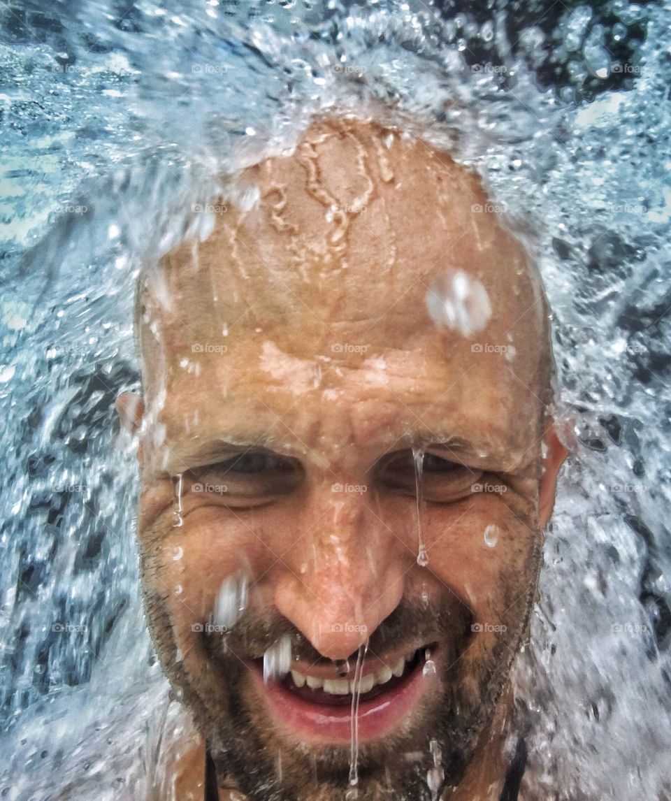 Close-up of a mature man's face with flowing water