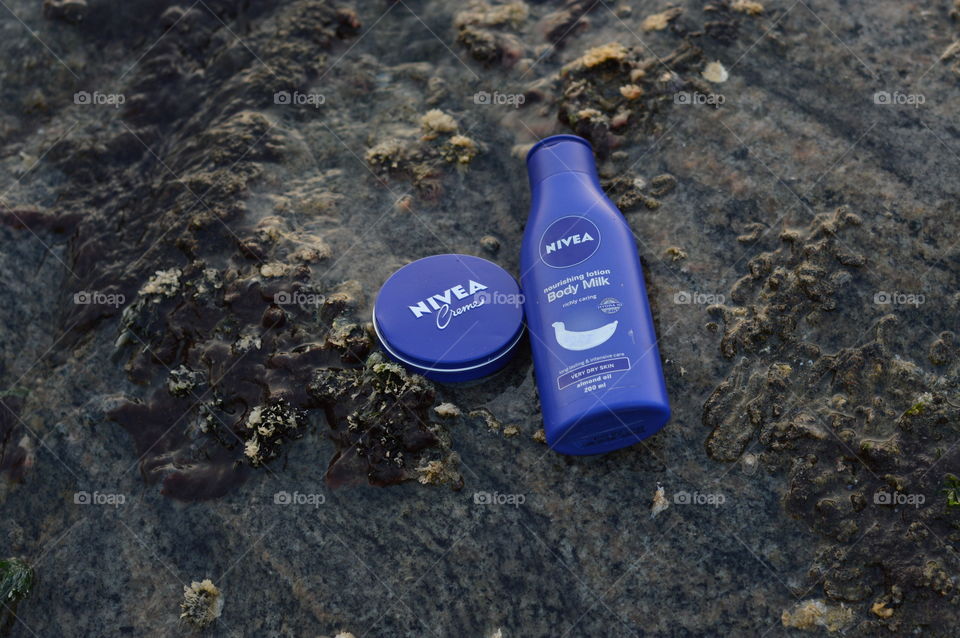 Nivea creme and Nivea body lotion are flaunted on the sea rock covered by beautiful Leathesia or Marine algae.