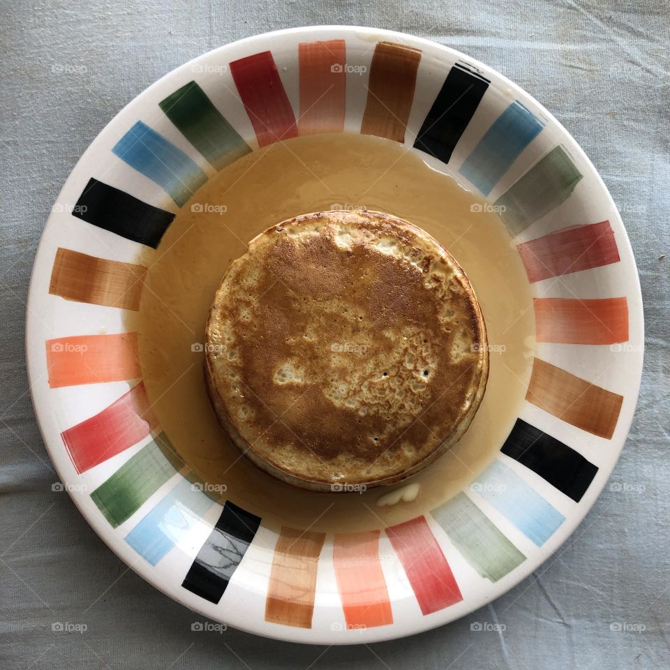 Pancake covered and surrounded by Maple Syrup on A hand painted plate Forming a sequence of circles