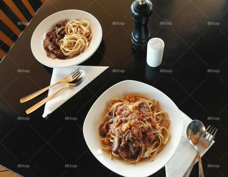 two plates of whole wheat linguini with meat in tomato sauce