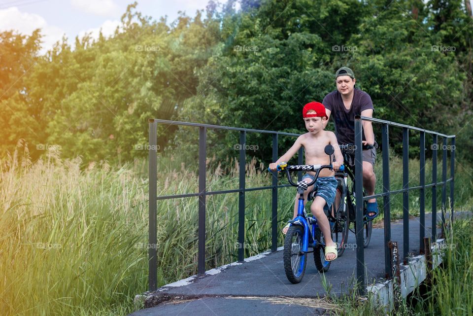 Father and son have fun together, ride bikes in the summer in the countryside, sunny day