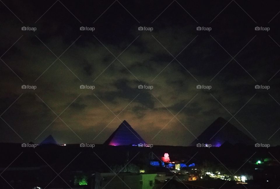 Iluminated piramids with purple lights in the evening with pre-storm, dark cloudy sky