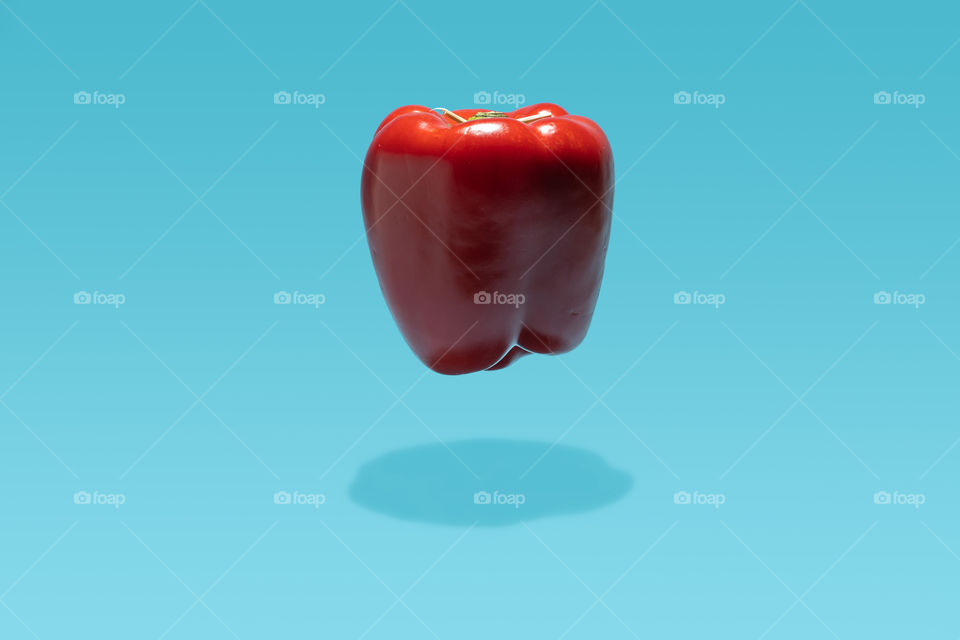 Red bell pepper floating on a blue background