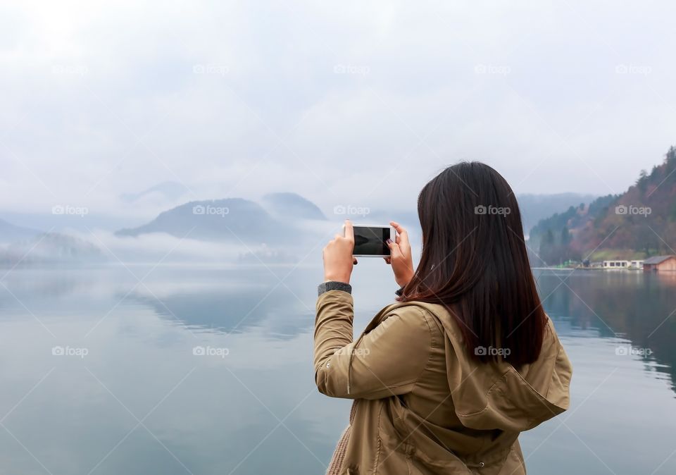 Woman photographing in front of lake
