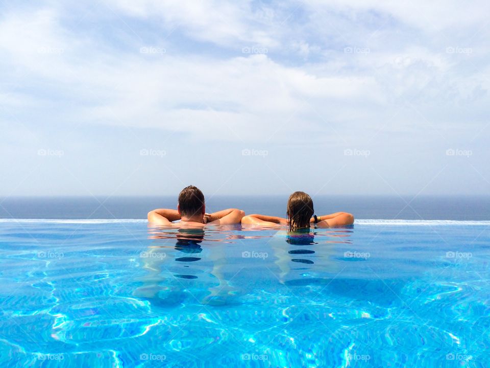 Rear view of couple in infinity pool