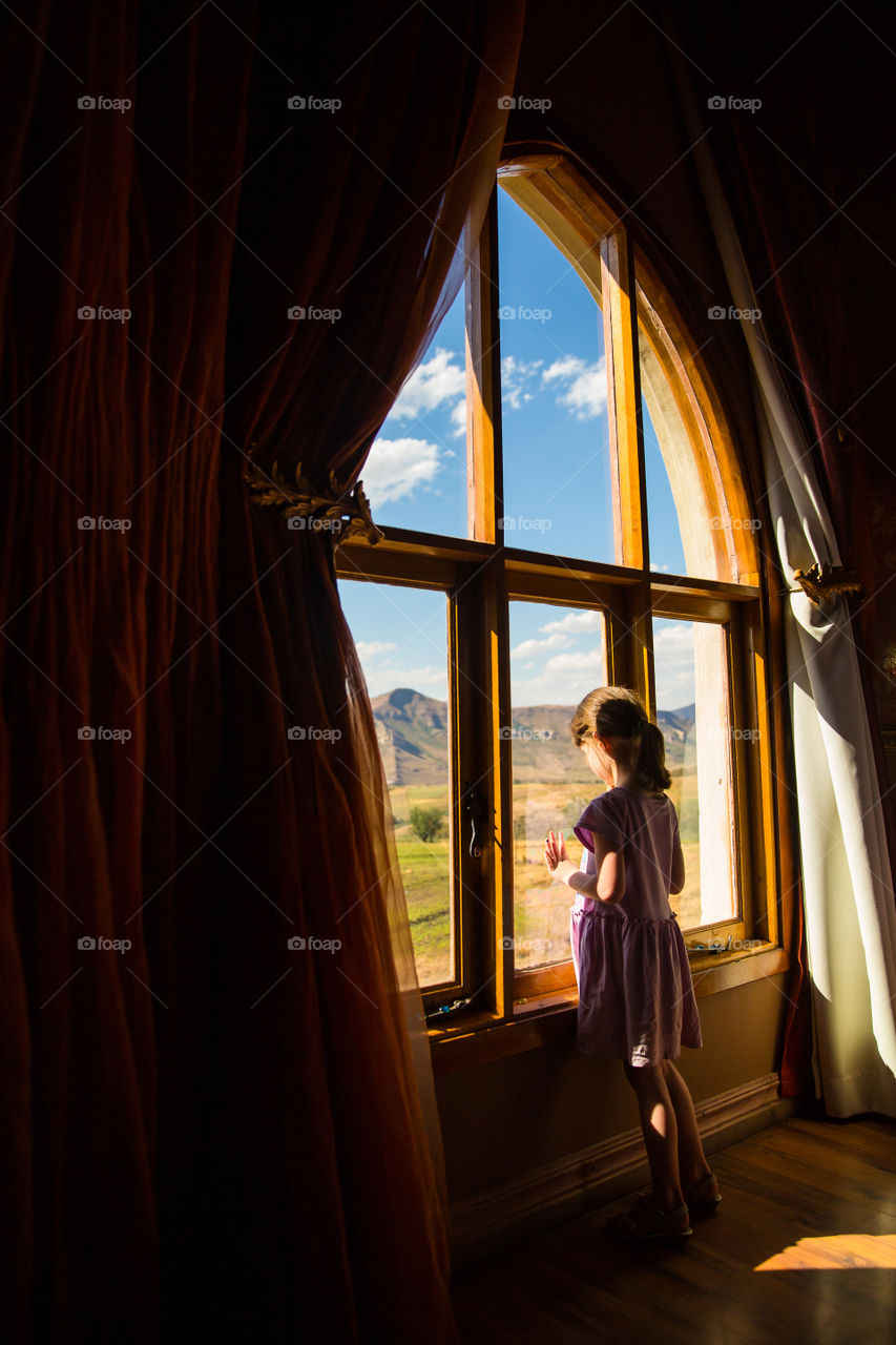 What a beautiful moment when my girl took in the beautiful landscape scenery from a castle's window. Image of a girl looking out a window to the mountains. Image from Clarens South Africa