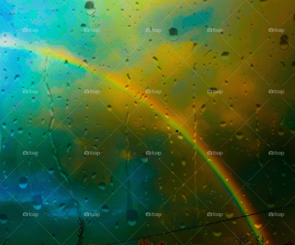 A rainbow viewed through a rain soaked window