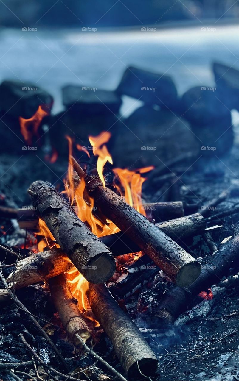 A fire on the ice provides warmth from the winds sweeping across the lake on a day for ice fishing.