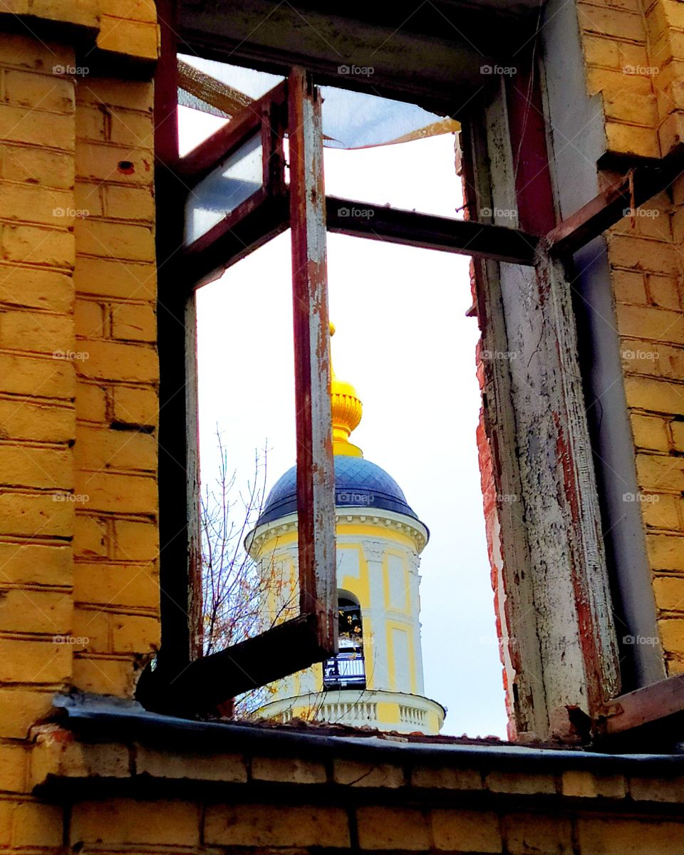 Part of the church through the window of a destroyed house