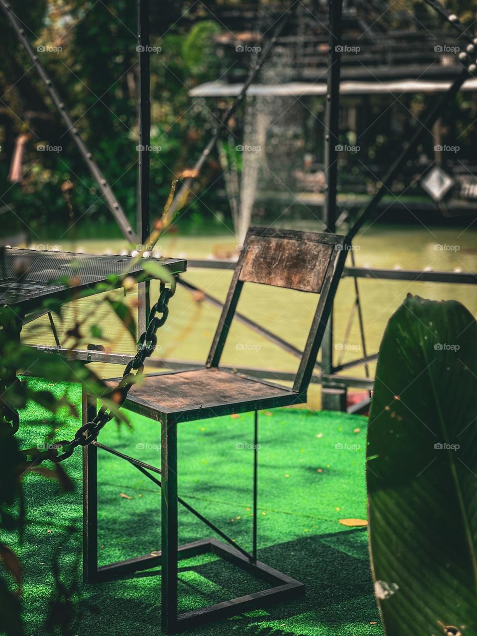 A wooden chair with a unique legs beside a pool