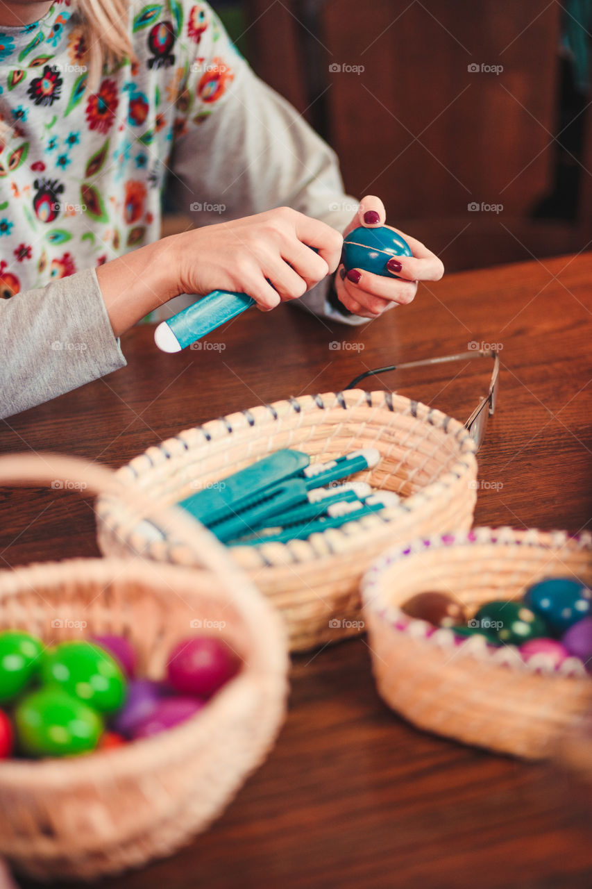 Woman decorating the Easter eggs by scratching patterns on dyed eggs. Traditional Easter time, spring time, new beginnings. Candid people, real moments, authentic situations